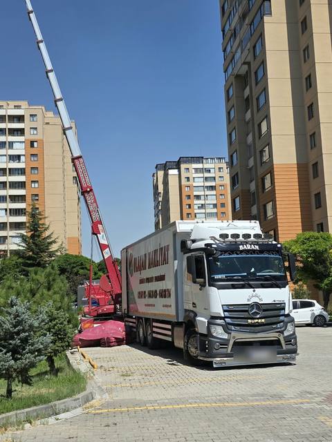 Yüksek bir apartmanın önünde mobil asansörün yanında duran Ulaşan Nakliyat kamyonu